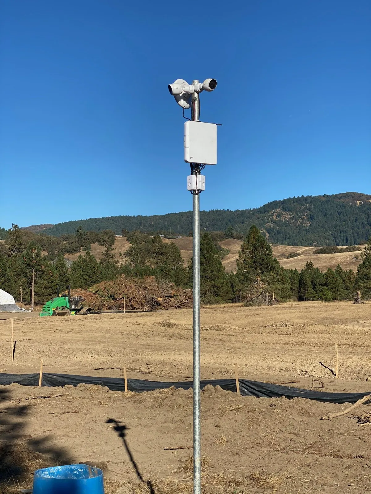 Security cameras on a steel pole with a wireless backhaul radio, in an open rural field