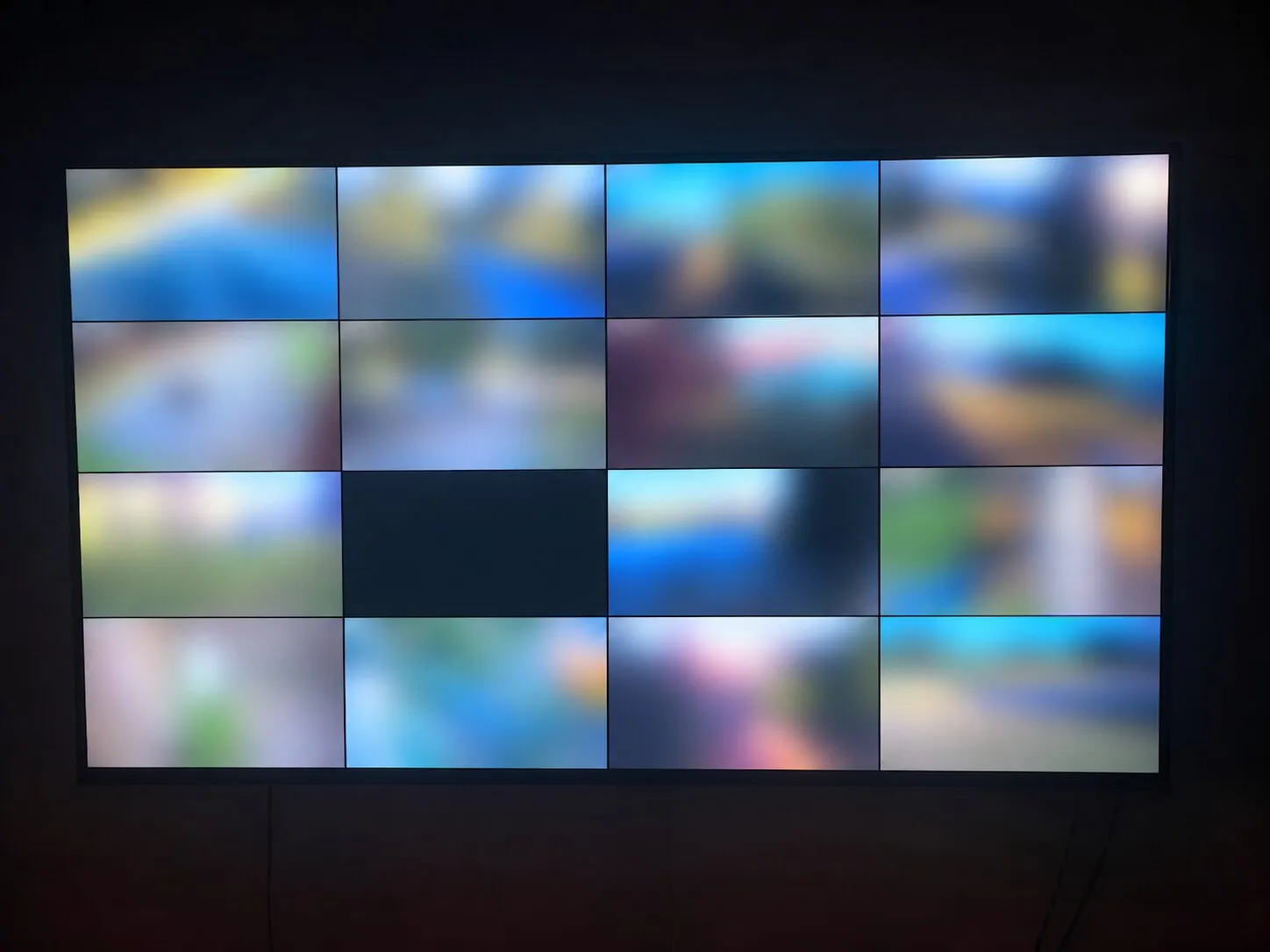 Wall-mounted display showing a sixteen-camera live view, with every camera image blurred to protect the client’s privacy